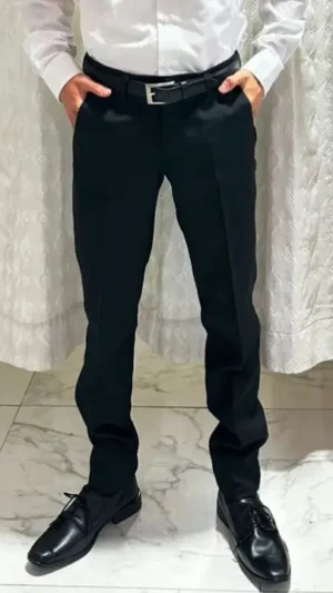 Pantalón de Vestir Negro Slim Fit - Con Brillo Sutil Hombre vistiendo pantalón de vestir negro ajustado slim fit con camisa blanca y cinto negro de sastrería juan